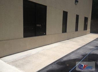 Clean commercial building concrete sidewalk restored after professional pressure washing service