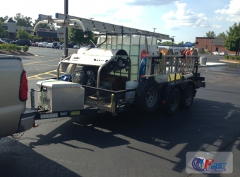 Professional commercial pressure washing trailer rig equipped with water tank, hose reels, and extension ladder hitched to a pickup truck