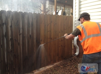 Professional pressure washing a wooden fence